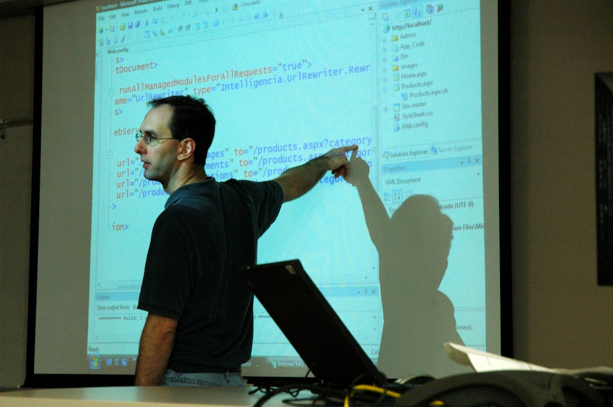Man teaching pointing to a projector screen.